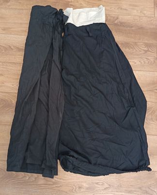 black and white skirt laying on the floor next to a pair of black pants