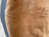 the back view of a person wearing brown pants with angel wings on them