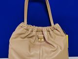 un sac à main beige avec une anse jaune posé sur une table blanche