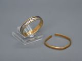 une bague en or et une autre bague en or posées sur une surface blanche