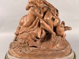 une statue antique en bronze représentant une femme et un chien, posée sur un socle en marbre