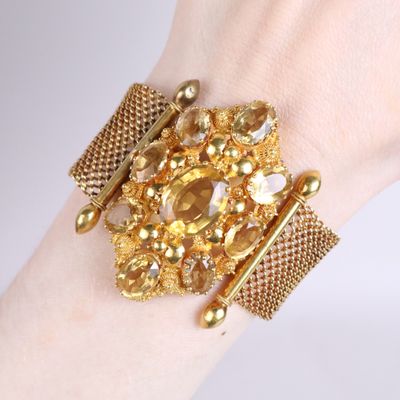 someone is wearing a gold bracelet with a bunch of jewels on it