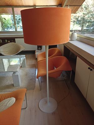 des chaises orange et une table dans un salon où se trouve un grand lampadaire