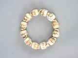 une photo d'un bracelet composé de perles en os et orné de têtes de mort