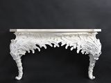 a white console table with a carved design on the top