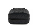 the black quilted bag is sitting on a white surface