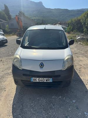 the small car is parked on the side of the dirt road