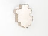 un morceau de papier sur lequel une croix a été découpée, posé sur une surface blanche