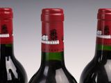 three bottles of red wine are lined up on a table