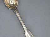 a silver spoon with a spoon handle on a gray surface