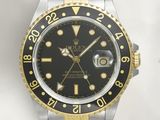a rolex watch with a black dial and gold bezel