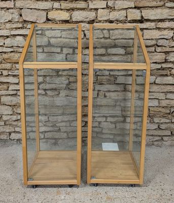 a pair of wooden and glass display cases with a brick wall in the background