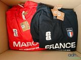 trois t-shirts dans une boîte en carton sur laquelle sont apposées des étiquettes