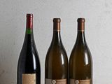 three bottles of wine are lined up on a wooden table
