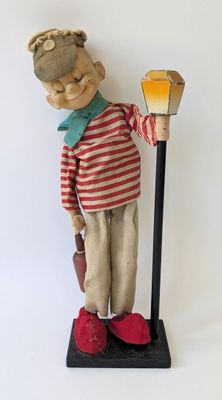a wooden statue of a man holding a lamp post
