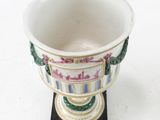 a white cup with a design on it sitting on a black base
