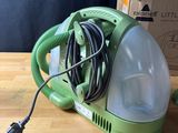 a green vacuum that is sitting on a wooden table