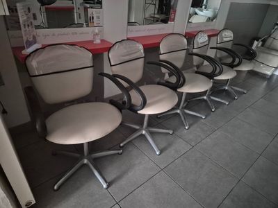 cinq fauteuils alignés en rang dans un salon de coiffure