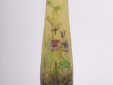 a yellow vase with flowers on it sitting on a stand