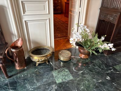 un vase de fleurs posé sur un sol en marbre, à côté d'une chaise
