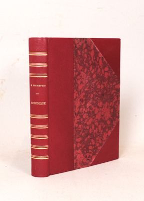 un vieux livre à la couverture rouge posé sur une surface blanche