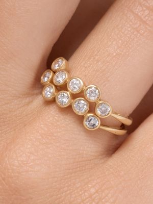 un gros plan de la main d'une personne tenant une bague en or sertie de trois diamants
