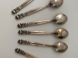 six silver spoons are arranged in a circle on a white surface