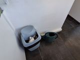 a cat sitting in a litter can next to a door