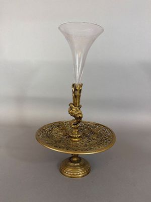 une plaque en laiton sur laquelle est posé un vase en verre, posée sur une table
