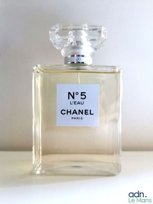 un flacon de parfum Chanel n° 5 posé sur une table, sur fond blanc