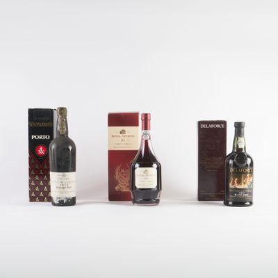 trois bouteilles de vin et une boîte de chocolats posées sur une surface blanche