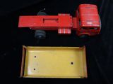 a red toy truck and a yellow box on a black surface