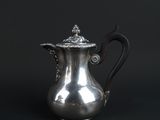 an antique silver coffee pot on a black background