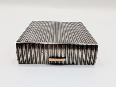 une image représentant une boîte argentée posée sur une surface blanche
