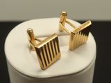two gold cufflinks on a white cake on a black table