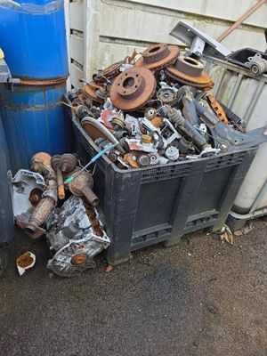 un tas de vieilleries dans une poubelle à côté d'un fût bleu
