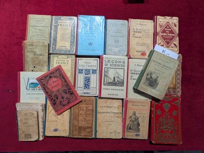 de nombreux livres anciens posés sur une table recouverte d'une nappe rouge