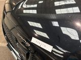 a black car parked in a parking lot with a sticker on the hood