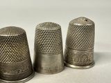 three silver thimbles sitting next to each other on a white surface