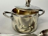 a silver pot and spoon sitting next to each other