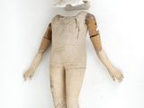 an old wooden doll with a white shirt and brown pants
