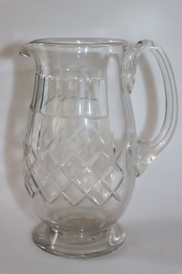 un pichet en verre transparent posé sur une surface blanche
