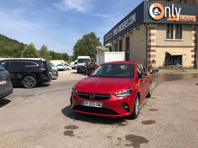 une voiture rouge garée devant un immeuble, sur un parking