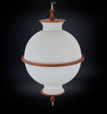 une lampe blanche suspendue à un poteau en bois sur fond noir