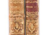 two old books sitting on top of each other on a white surface