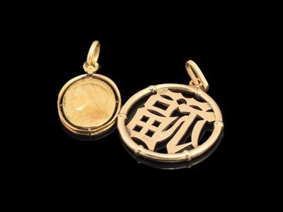 un gros plan sur deux pendentifs en or ornés de caractères chinois