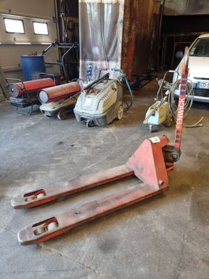 un petit camion garé dans un garage, à côté d'un chariot élévateur