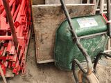 a green wheelbarrow that is sitting in the dirt