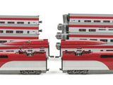 two red and white trains sitting side by side on a white surface
