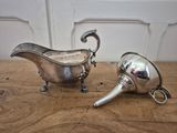 two silver plated items on a wooden table with a white wall